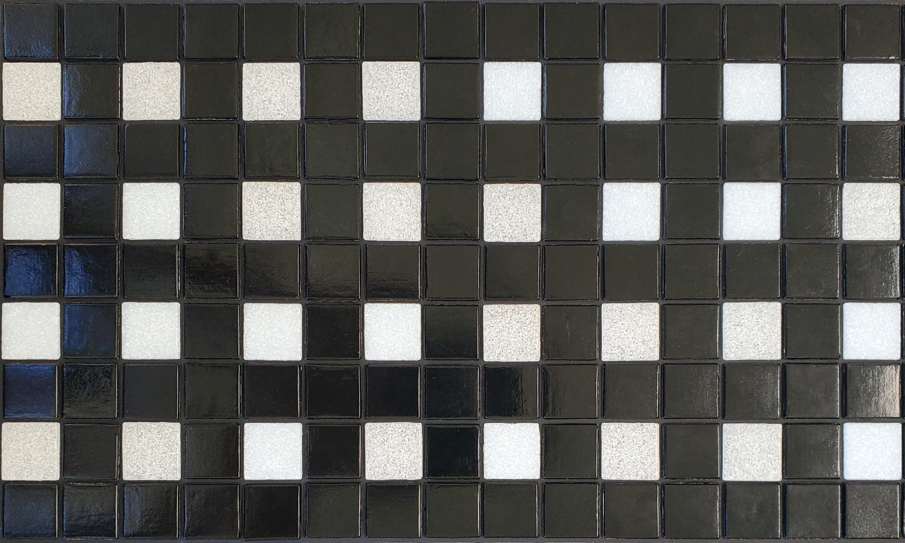 Parker D - modernism-inspired checkerboard glass mosaic waterline pool border tile - glossy black and white tiles in a punctuated grid.